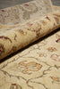 Load image into Gallery viewer, A close-up of a rolled area rug showing its cream and beige base with traditional floral motifs in muted burgundy, olive green, and tan.