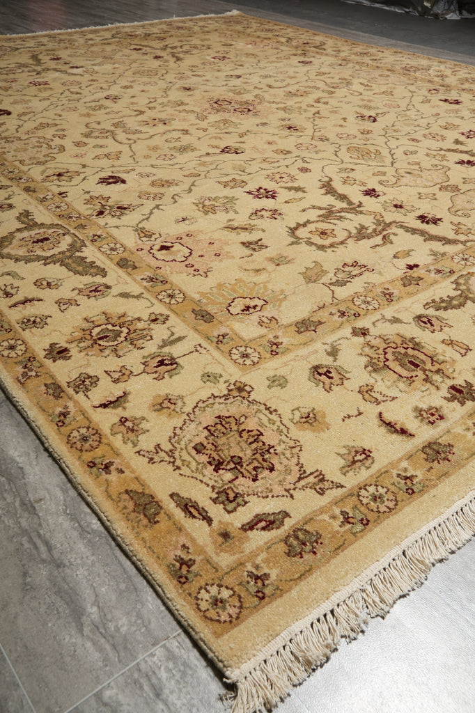 A traditional oriental area rug with an intricate floral and medallion pattern in beige, brown, and muted red tones, shown laid out on a gray tiled floor.