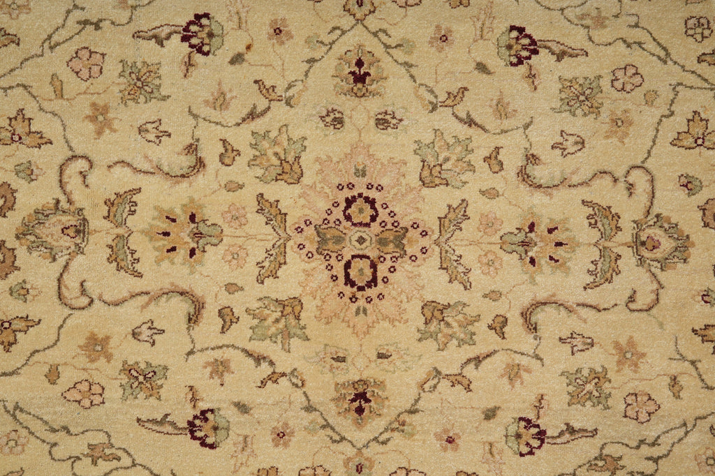 A close-up of a traditional patterned rug with a beige background and intricate floral motifs in muted brown, green, and dusty pink.