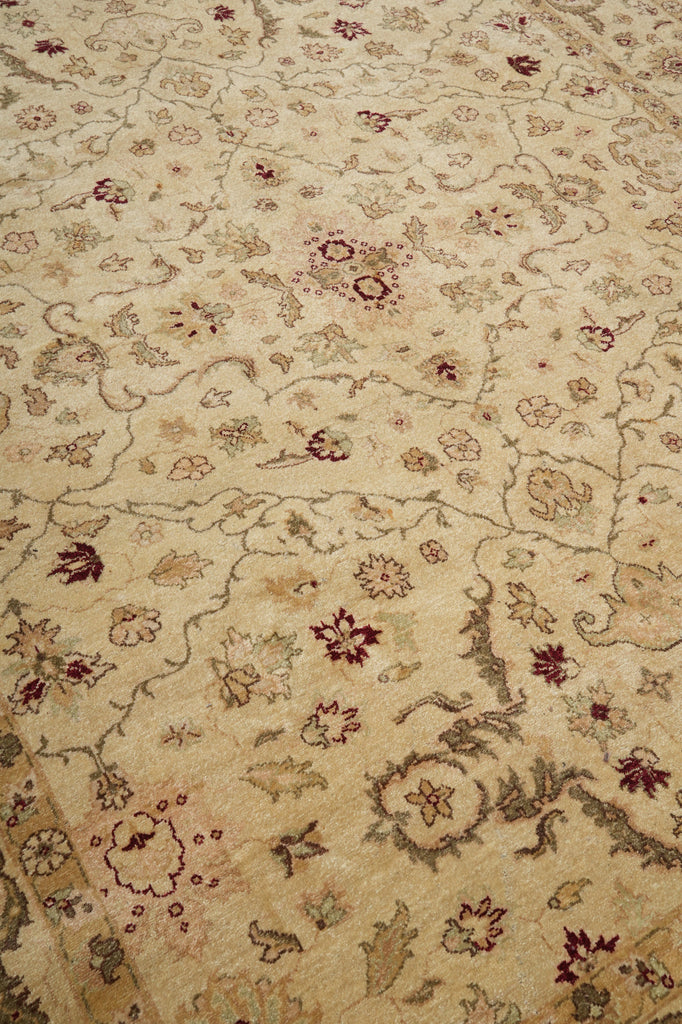 A close-up of a traditional patterned rug with a beige base and floral motifs in muted brown, gray, and burgundy.