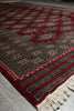 Load image into Gallery viewer, A close-up of a patterned area rug with cream fringe, featuring red, black, and beige geometric and floral motifs.