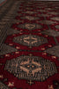 Load image into Gallery viewer, A close-up view of a traditional patterned rug with a deep red field, beige and black geometric medallions, and small cream accents.