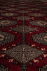 Load image into Gallery viewer, A close-up view of a traditional patterned rug with a deep red field, beige and black geometric medallions, and small cream accents.