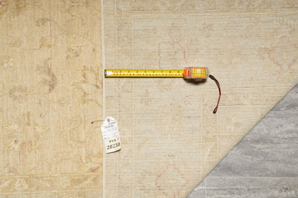 A beige textured rug or flooring sample shown with a yellow tape measure laid across it and a small inventory tag.