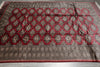 Load image into Gallery viewer, A large traditional area rug with a dark gray and red geometric pattern, laid flat on a gray floor.
