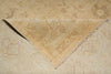 Load image into Gallery viewer, A close-up of a folded beige area rug showing its woven texture and subtle distressed floral patterns.