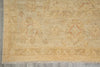 Load image into Gallery viewer, A close-up of a vintage-style area rug with a distressed beige and tan base, featuring faded red diamond medallions and traditional geometric borders, laid out on a gray tiled floor.