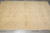 Load image into Gallery viewer, A large rectangular area rug with an intricate traditional floral pattern in shades of beige, tan, and light brown, laid out on a gray tiled floor.