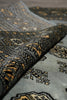 Load image into Gallery viewer, Close-up of a folded area rug showing its detailed woven pattern in charcoal gray, black, and ochre gold.