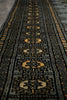 Load image into Gallery viewer, Close-up of a patterned textile or rug showing a dark charcoal base with repeating geometric medallion motifs in beige and muted gold.
