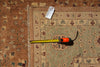 Load image into Gallery viewer, A close-up of a patterned area rug with a tape measure and price tag laid on top to show dimensions and condition.