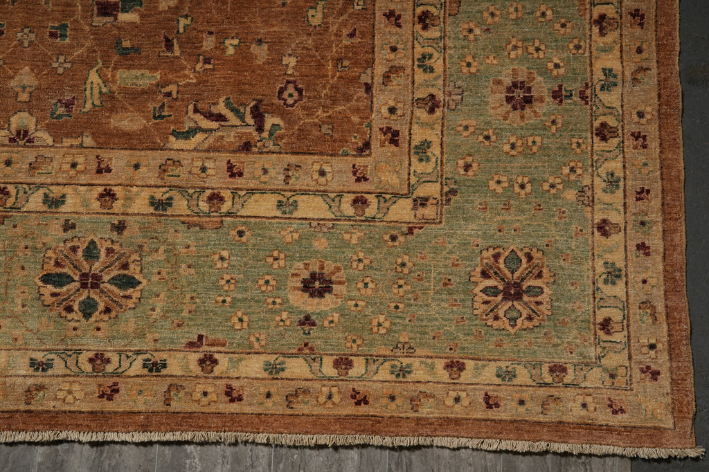 A close-up of an antique-style oriental rug showing its corner, featuring a sage green field, a brown border, and traditional floral motifs.