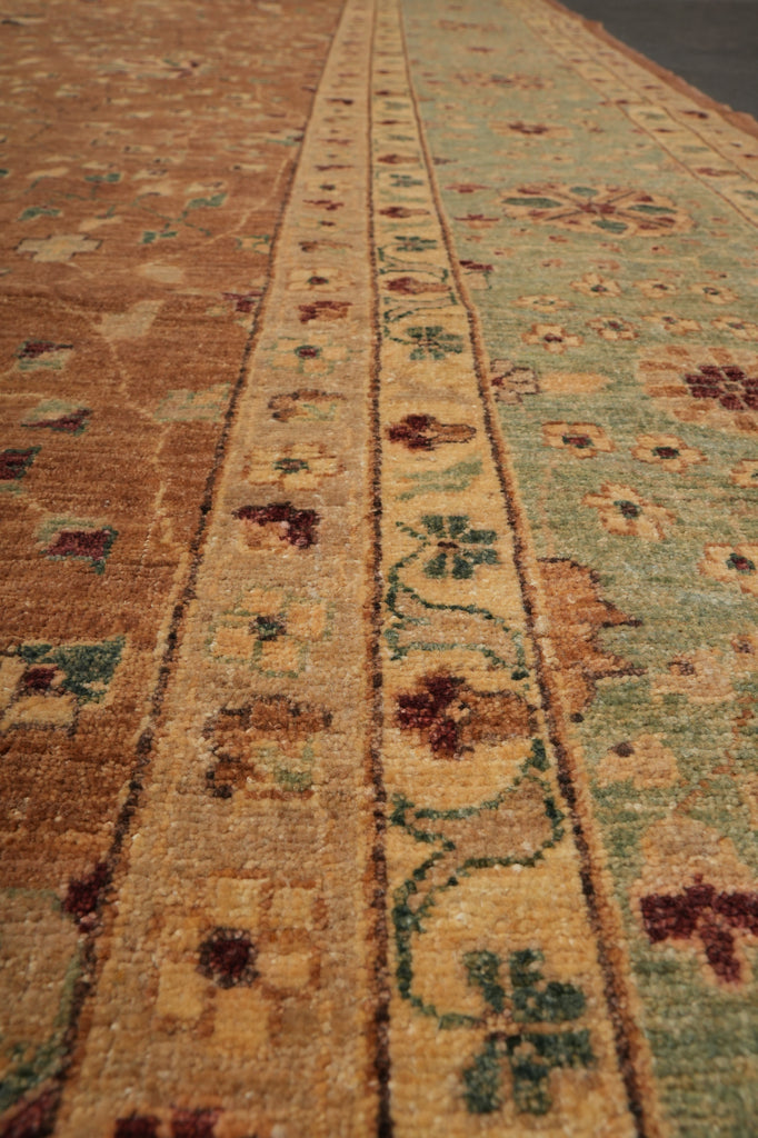 A close-up view of a traditional patterned area rug showing its detailed woven texture and multi-colored floral motifs in shades of beige, brown, and sage green.