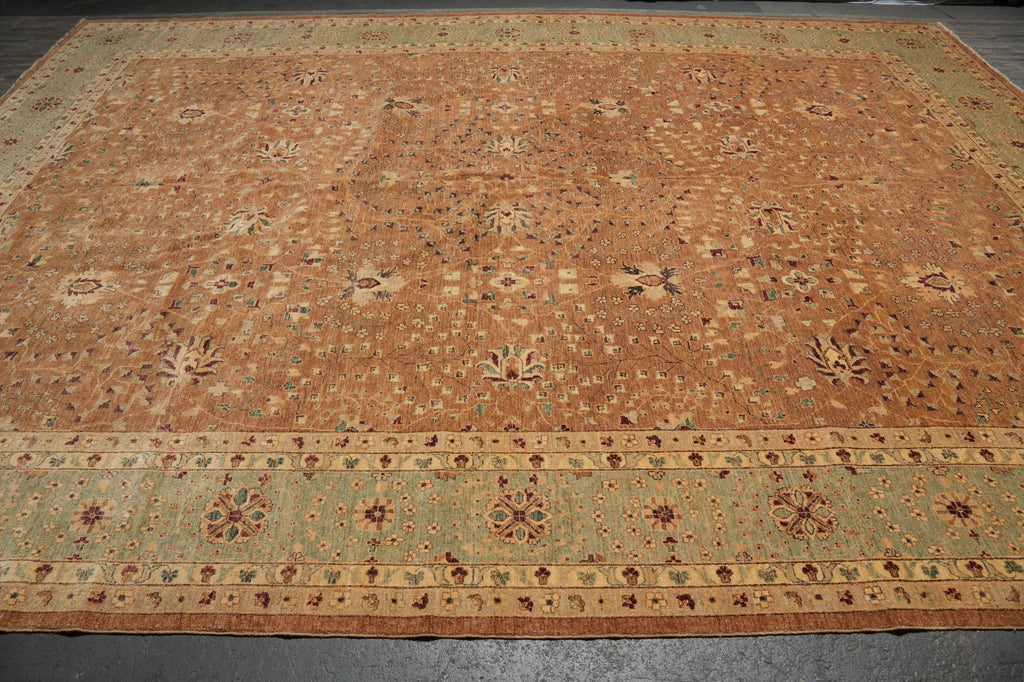 A large rectangular area rug with an intricate traditional pattern, featuring a warm tan and brown field with a contrasting light green and beige border.