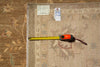 Load image into Gallery viewer, A square area rug laid flat on a matching patterned floor, with a yellow tape measure extended along one edge and two small tags near the top corner.