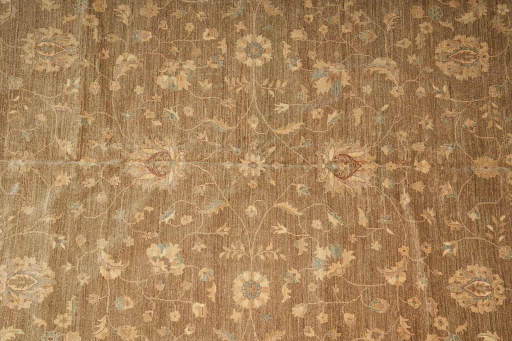 A close-up of a traditional patterned rug with a warm brown base, beige floral motifs, and light blue accents.