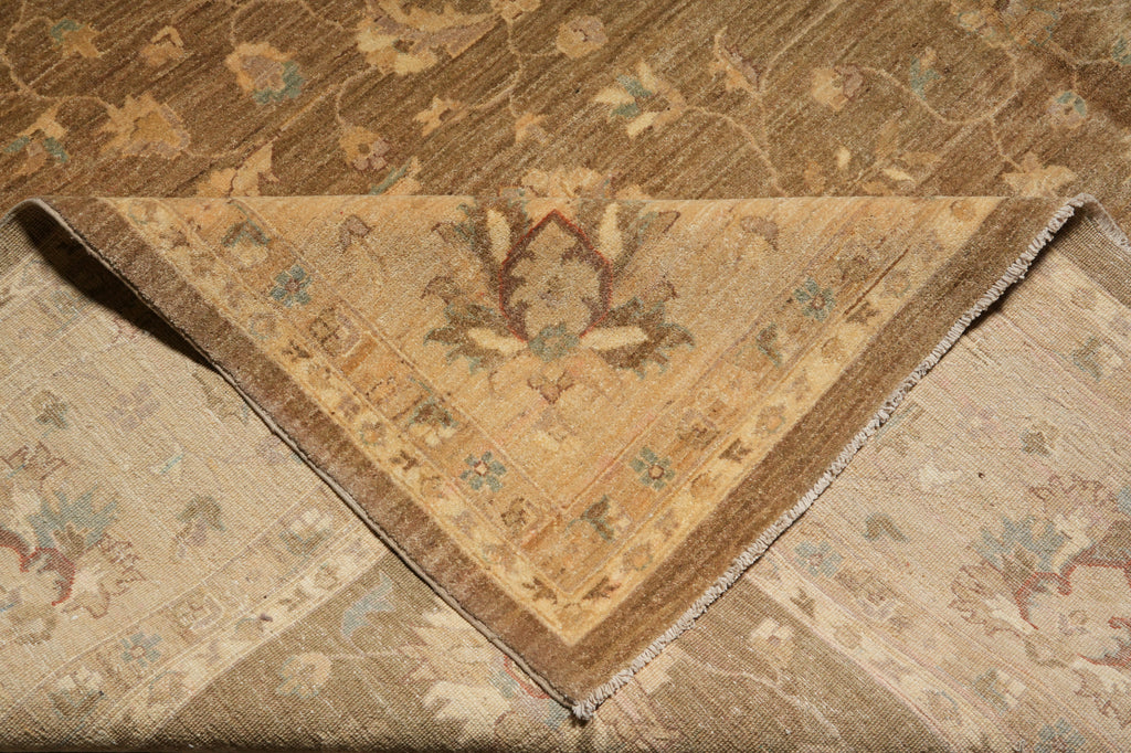 A close-up of a folded vintage-style area rug showing its intricate floral and geometric patterns in warm beige, brown, and muted blue tones.