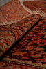 Load image into Gallery viewer, A close-up of a folded patterned rug showing its woven texture and traditional design in red, orange, black, and beige tones.