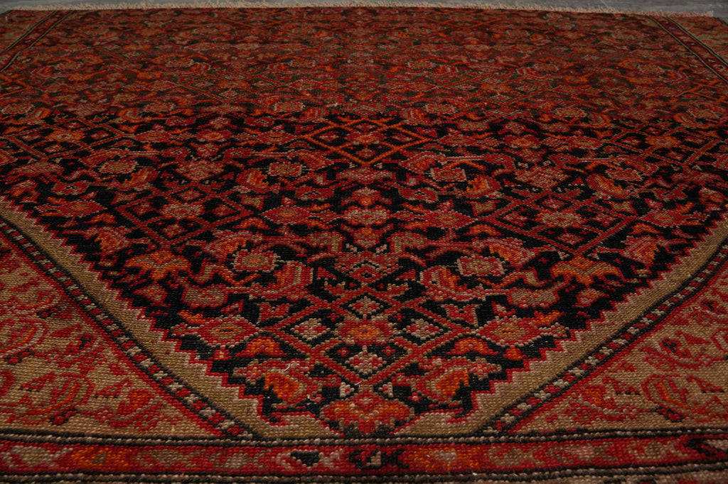 A traditional Persian-style area rug with an intricate floral and geometric pattern in deep red, black, and beige.
