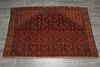 Load image into Gallery viewer, A traditional Persian-style area rug with a dark red and black central field, floral motifs, and a patterned border, laid flat on a gray tiled floor.