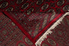 Load image into Gallery viewer, A close-up of a traditional patterned rug with a deep red field, geometric borders, and off-white fringe.