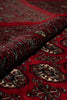 Load image into Gallery viewer, A close-up of a folded red patterned rug or textile with intricate geometric and floral motifs in dark brown, beige, and black.