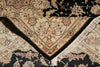 Load image into Gallery viewer, A close-up of a traditional oriental rug with a cream and black floral pattern, featuring a V-shaped corner with fringe trim.
