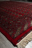 Load image into Gallery viewer, A close-up of a traditional patterned rug with a deep red field, cream fringe, and beige, blue, and black geometric motifs.