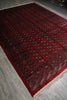 Load image into Gallery viewer, A traditional Persian-style area rug with a deep red field, intricate geometric and floral motifs in beige and black, and cream fringe on the ends, shown laid out on a gray tiled floor.