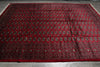 Load image into Gallery viewer, A large red Persian-style area rug with intricate black, brown, and beige geometric and floral patterns, laid flat on a gray tiled floor.