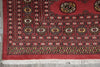 Load image into Gallery viewer, A close-up of a red patterned rug with white fringe, featuring geometric borders and floral motifs in black, beige, and yellow.