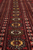 Load image into Gallery viewer, A close-up view of a traditional patterned rug with a deep red field, black borders, and repeating medallion motifs in yellow, cream, and brown.
