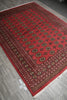 Load image into Gallery viewer, A red Persian-style area rug with intricate circular medallion patterns and detailed borders, shown laid out on a gray tiled floor.