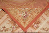 Load image into Gallery viewer, A close-up of a decorative textile or rug corner showing an ornate floral and scroll pattern in warm peach, beige, pink, and muted green tones.