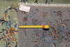 Load image into Gallery viewer, A close-up of a patterned area rug with a muted blue-gray base and floral motifs in orange, blue, and cream, shown with a yellow tape measure and a small inventory tag.