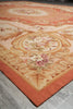Load image into Gallery viewer, A close-up of an ornate area rug with a warm peach and beige floral pattern, featuring a solid rust-orange border, laid on a gray tiled floor.