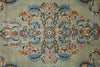 Load image into Gallery viewer, A close-up of an ornate floral patterned textile or rug with a muted sage green background and detailed motifs in blue, rust orange, and cream.
