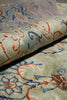 Load image into Gallery viewer, A close-up of a folded area rug showing its detailed pattern and pile texture. The rug features a muted sage green base with intricate floral and scroll motifs in blue, rust orange, and cream.