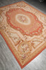 Load image into Gallery viewer, A rectangular vintage-style area rug with an ornate floral and scroll pattern, shown laid out on a gray tiled floor.