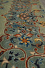 Load image into Gallery viewer, A close-up view of an ornate area rug with a traditional floral and scroll pattern on a muted sage green background, featuring accents of blue, rust red, orange, and cream.