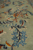 Load image into Gallery viewer, Close-up of a patterned area rug with a light sage green base and an intricate floral design in blue, orange, beige, and dark navy.