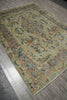 Load image into Gallery viewer, An ornate traditional area rug with a sage green base and intricate floral motifs in blue, orange, and beige, shown on a gray wood-look floor.