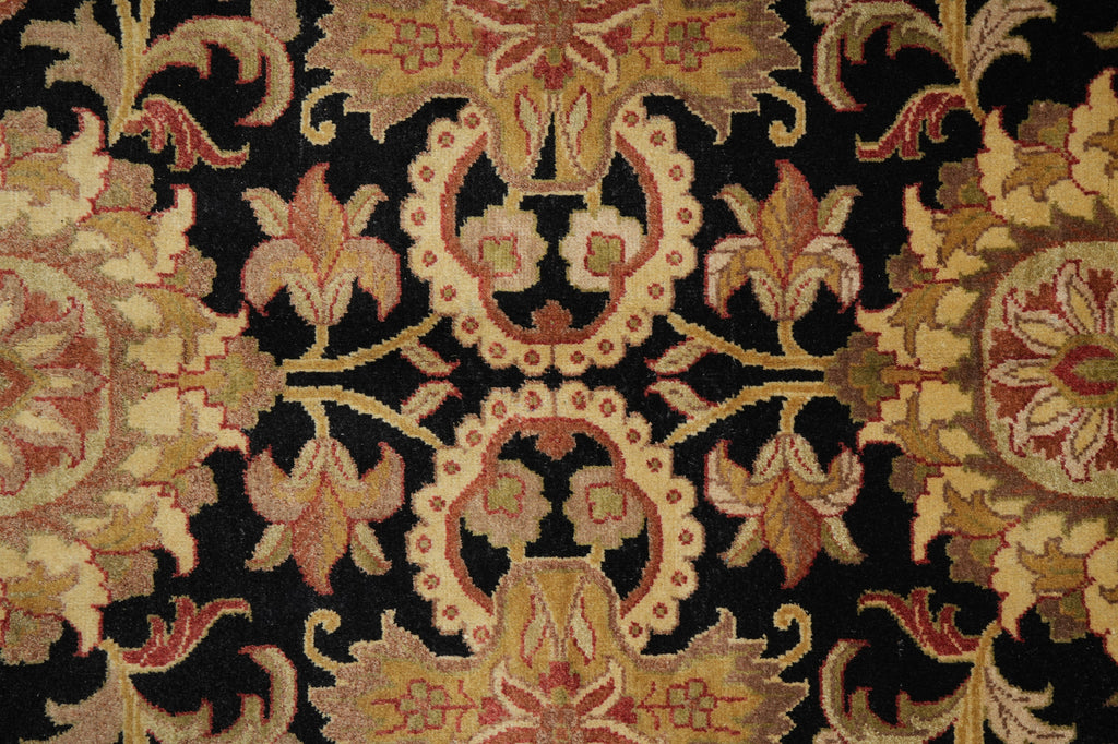 Close-up of an ornate floral patterned textile or rug with a black background and cream, tan, muted red, and gold motifs.