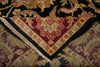 Load image into Gallery viewer, Close-up of a patterned area rug corner showing a deep red central field, beige and gold floral motifs, black borders, and cream fringe, layered over other rugs.