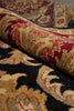 Load image into Gallery viewer, A close-up of a folded area rug showing its detailed pattern and pile texture. The rug features a complex traditional design with a black base, prominent gold and beige floral motifs, and deep red sections.