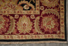 Load image into Gallery viewer, Close-up of an ornate patterned area rug corner showing deep red, beige, black, and muted green floral motifs with fringed edge and woven texture.