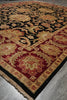 Load image into Gallery viewer, A traditional oriental-style area rug with an intricate floral and scroll pattern, featuring a black field, deep red borders, and beige and gold accents, laid out on a gray concrete floor.