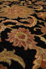 Load image into Gallery viewer, Close-up of a traditional patterned rug with a black background and floral motifs in beige, gold, and muted red.