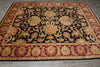Load image into Gallery viewer, An ornate rectangular area rug with a black center field, featuring large floral medallions and scrolling vine motifs in gold, red, and beige, surrounded by a detailed patterned border, shown on a gray tiled floor.