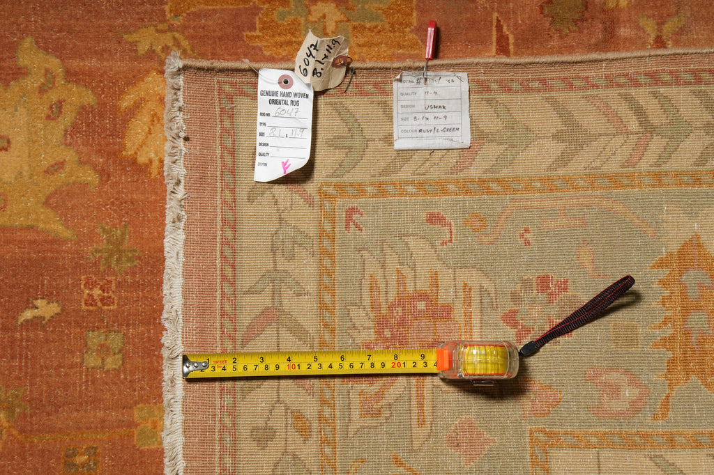 A vintage-style area rug with a beige, orange, and pink pattern, shown with a yellow tape measure and size tag.
